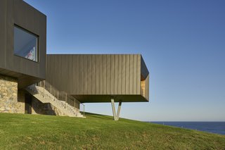 The funnel-like protrusion cantilevers over the hillside and is supported by angled pillars.