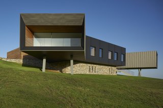 This full-height glazed wall and balcony look out toward dramatic framed views of the sea. 