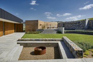 Perched on a coastal site in Australia, this property features cantilevered views of the sparkling sea. The home wraps around a courtyard that mixes a material palette of metal, wood, stone, and concrete. 