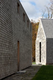 A Minimalist, Rick Joy–Designed Farmhouse in Vermont Asks $9.25M - Photo 2 of 12 - The elongated, gabled house is clad in cedar shingles and features massive end walls that have been crafted from Lake Champlain bedrock. 