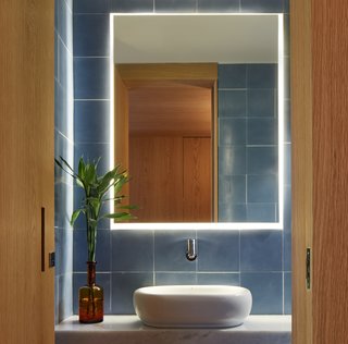 A deep, earthy blue tile plays off the richness of the wood in this bathroom. 