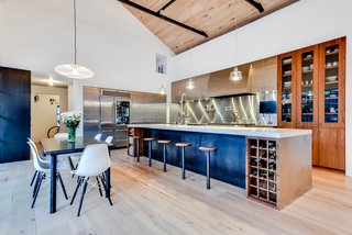 Own This Alluring Sculptural Abode in Austin For $3.1M - Photo 4 of 21 - Here is a look at the kitchen and dining area from the other angle. The handmade black-walnut cabinets are elegantly juxtaposed against the use of stainless steel. More so, all of the steel beams, railings, and other metalwork in the home were originally handcrafted onsite by local blacksmiths.