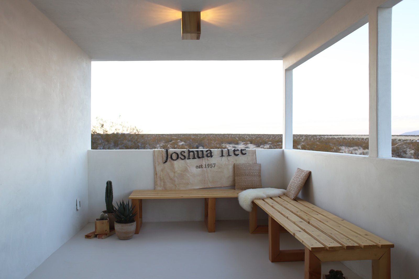 Qn the opposite end of the covered patio the Smirkes built two long benches that overlook the open desert. The canvas is a flag they had made by Lindsay Smith of Makers Workshop that says, “Joshua Tree Est. 1957” the year the original cabin was constructed.
