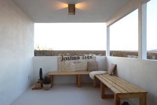 Qn the opposite end of the covered patio the Smirkes built two long benches that overlook the open desert. The canvas is a flag they had made by Lindsay Smith of Makers Workshop that says, "Joshua Tree Est. 1957," which is the year the original cabin was constructed.