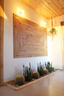 Brian created the wooden artwork from repurposed wood from the original structure. The glass front door even provides enough natural sunlight that the couple were able to plant an in-floor cactus garden. However, before they could get started, they had to remove a section of the concrete with a rented a jackhammer from Home Depot to accommodate the installation. 