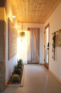 The Smirkes moved the entrance to the side of the home to maximize privacy. The use of a glass front door keeps the entryway bright and airy. The curtain blocks a small storage closet. 