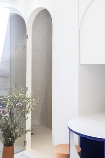 The compact bathroom is tucked away behind an arched-shaped mirror.
