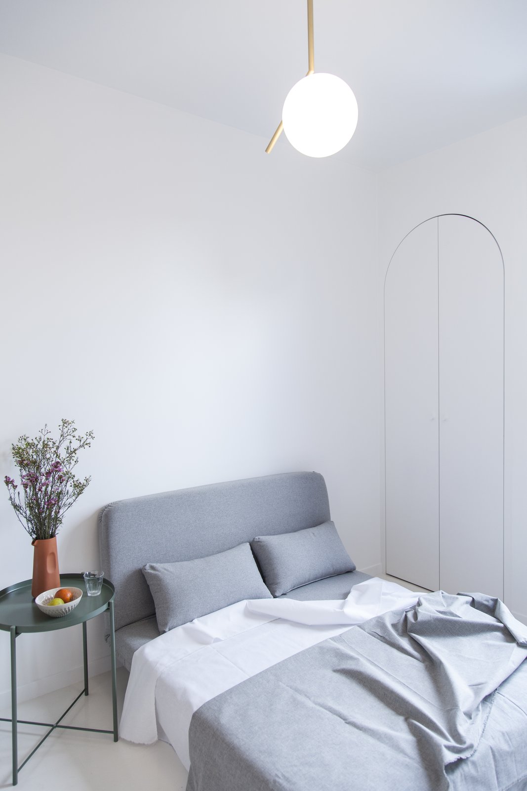 A bedroom/living room includes a sofa-bed, a small side table, and some arched-shaped closet space.
