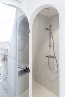 The bathroom features light gray tiles, a shower, sink, and toilet. 