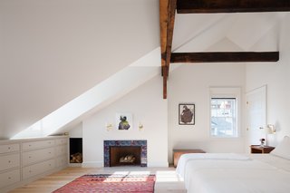 Another big architectural move was to redefine the unfortunate layout of the upstairs master suite. Yun moved the bedroom to one side and put the bathroom behind a wall. The purple-blue tiles around the fireplace were designed by one of the owners and represent clocks with different hours—a reference to how watching the fire can be the best way to pass the time. 