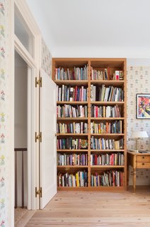 The designers fortunately happened on enough antique wallpaper to outfit the whole room. The bookshelf is a custom design by Yun and made of salvaged heart pine, same as the floor. It features grooves in the sides, so the shelves can be pulled in and out. 