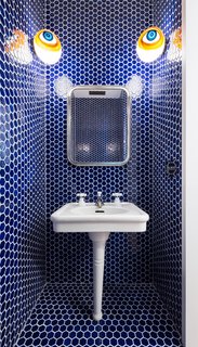 The blue tiles in the powder room reference one of the homeowner’s artworks. The eyes at the top are vintage globes from a former optometrist's shop. The sink is also a vintage piece from Demolition Depot—in fact, most of the home's plumbing are repurposed pieces. 