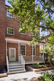 The porch was legalized and rebuilt with cast-iron columns, railings, and stone flooring in keeping within a refined, Federal-style aesthetic. 
