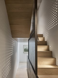 A perforated steel plate forms a wall between the staircase and the room.