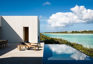 Outside, a shallow pool divides the coastline from the adjoining terrace, bringing the expanse of ocean water closer to the home's living spaces. 