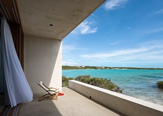 A terrace sits quietly against the water, not quite indoors and not quite outdoors. 