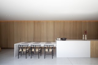 The light-filled kitchen is centered around a partially timber-clad island that matches the cabinetry.