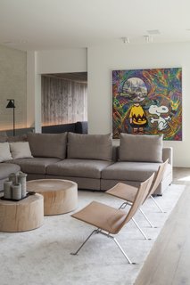 Recycled bricks that have been whitewashed play off the stone-colored sectional, tree-stump coffee tables, and leather chairs, while a dynamic work of art injects color and unexpected energy into the space. 