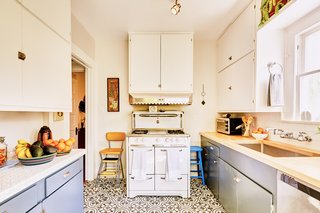 A charming kitchen features graphic floor tiles and is equipped with a vintage Wedgwood stove.