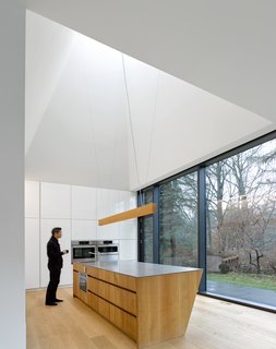 The kitchen anchors the south end of the home. Set in a double-height volume, the 20-foot-tall pyramidal ceiling creates an expansive space that opens to the creek, the courtyard, and above to the sky. 
