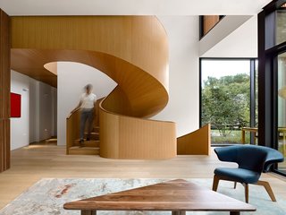 A wood-clad spiral staircase connects the living room to the second-floor master suite. 