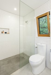 The bathrooms feature simple white tiles with concrete floors, while pocket doors throughout the home are painted in primary colors to create a subtle pop of bright color. 