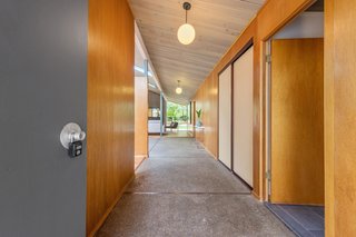 A corridor leads from the entrance to the open-plan living space. Note the original aggregate concrete flooring. 