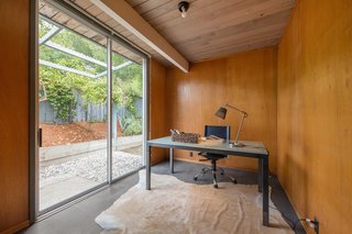 This is the bonus office space that is complete with original wood paneled walls and a sliding door to the patio. 