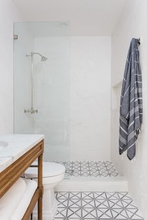 The updated bathroom in the hallway has been fitted with geometric floor tiles. 