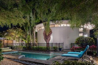 A heated pool is on the second lot and is surrounded by lush tropical greenery. 
