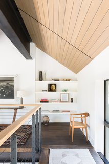 From the living room, an open floating staircase leads up to the balcony loft and the second-floor bedrooms. 