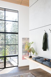 The entry features a custom-made floating bench. Hooks were added for convenience, as the mudroom would be the main point of entry after a day spent on the slopes.