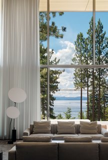 The minimalist material palette and two-story glass wall respond to the client’s desire to focus on the view of the lake, from water to treetops.