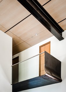 In the main living space, a glass-and-steel bridge is suspended above the kitchen area, becoming a viewport that draws the eye towards the lake.