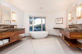 The master bath features stainless-steel fixtures and leathered sequoia brown marble on the custom-built walnut cabinetry. 