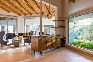 Terrazzo tile floors with solid brass are featured throughout the open plan layout. The cork inserts between the ceiling's vaulted beams were inspired by home's original design. 