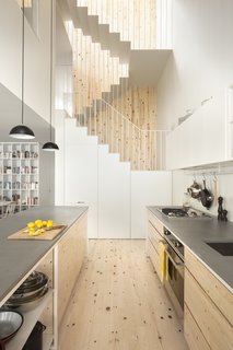 The kitchen faces the back garden and benefits from a double height atrium space. Pine has been used for the kitchen flooring and cabinets, a design element that is also picked up in the stairwell. The built-in refrigerator and pantry are cleverly hidden under the first flight of stairs. 