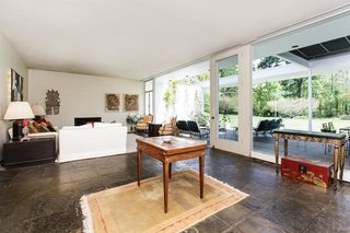 The living room features floor-to-ceiling windows and opens to a patio. 
