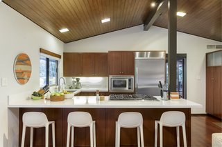 The open kitchen boasts stainless-steel appliances and warm, wood cabinetry. 