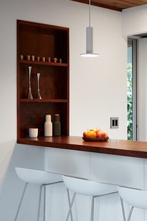 Walnut has been used for the kitchen bar top, as well as with the window sill/ledge, which adds warmth and contrast to the crisp white interiors.
