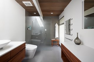 Bathroom updates also maintain the bright and airy feel of the rest of the home. The flooring is a large porcelain tile (24" x 24") in a neutral gray tone, serving as a uniform background against which the other materials can stand out.
