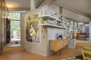 A central concrete wall serves as a divider between the kitchen and living room. 