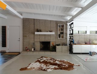 Inside, the home features an open floor plan and an exposed brick fireplace. 