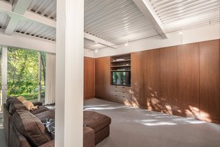 Ample storage—imperative for glass house living—is set behind sleek wood cabinets. 