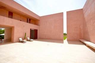 The home has been built around a central courtyard, with the surrounding exterior wall featuring a dramatic cut-out that inserts both light and shadows into the design.