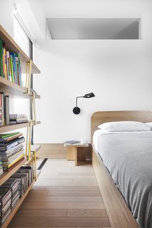 The bedroom is predominately oak with a custom-designed bed and nightstand. The lighting in this room is also by Sangaré.