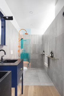 The bathrooms are a break from the minimalist aesthetic of the living spaces, injecting color and interesting finishes that include the use of a dichroic glass shower divider. 