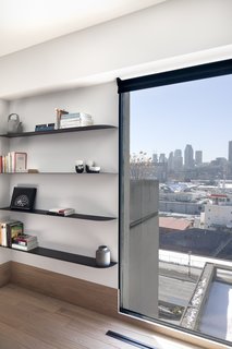 The window in the living room is framed by built-in shelves. The owners are collectors of local craft and design, and had ventilation grids custom-made specifically for the renovation. 