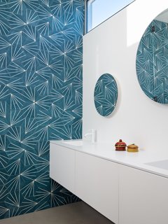 Bright, colorful wallpaper adds a fun touch of midcentury vibes to the bathroom.