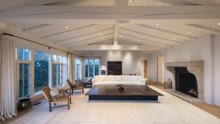 The expansive living room is anchored by the oversized wood-burning fireplace and features a vaulted ceiling with exposed beams that have been painted a clean, crisp white. 